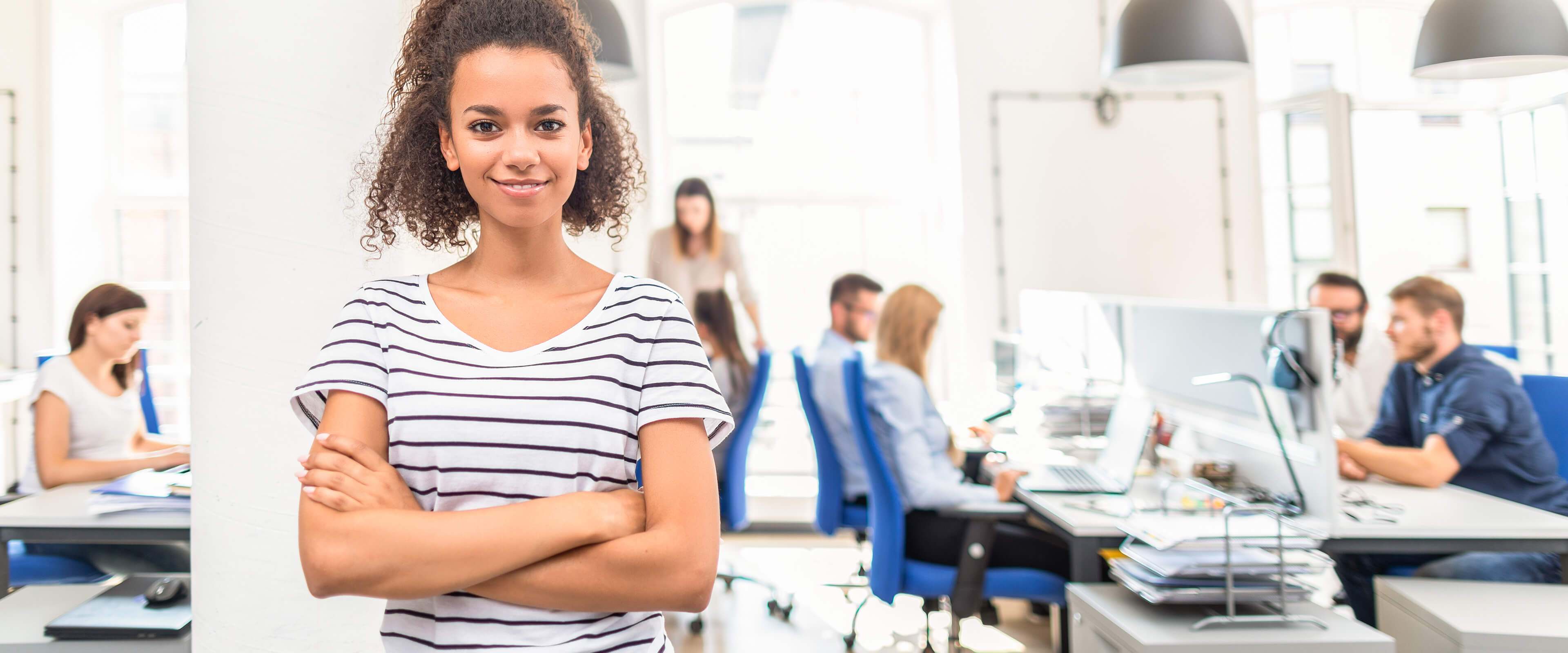 Mitarbeiterin steht in einem Großraumbüro